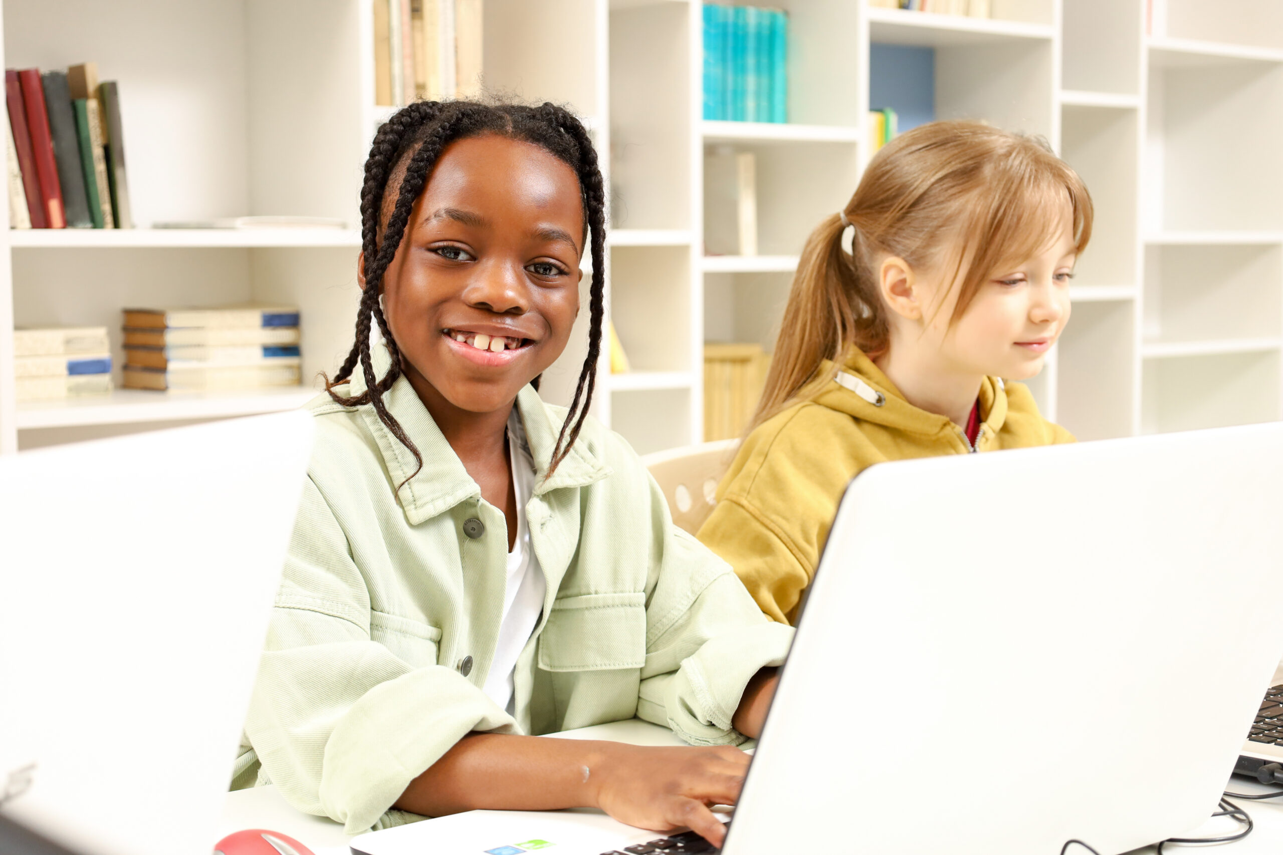 African American boy sitting at the table in computer science class. Kids playing computer games. Education, learning and people concept