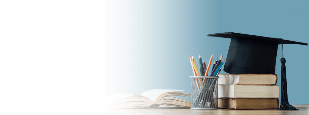 Graduation cap on top of a stack of books next to a container filled with pencils